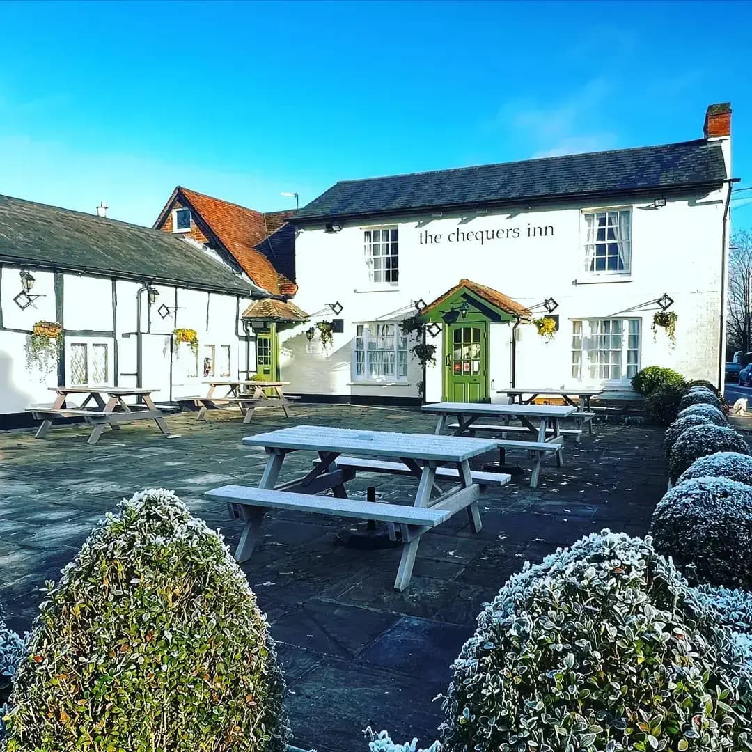 Exterior shot of the Chequers Inn gastro-pub, showing the quaint outdoor seating area in winter.