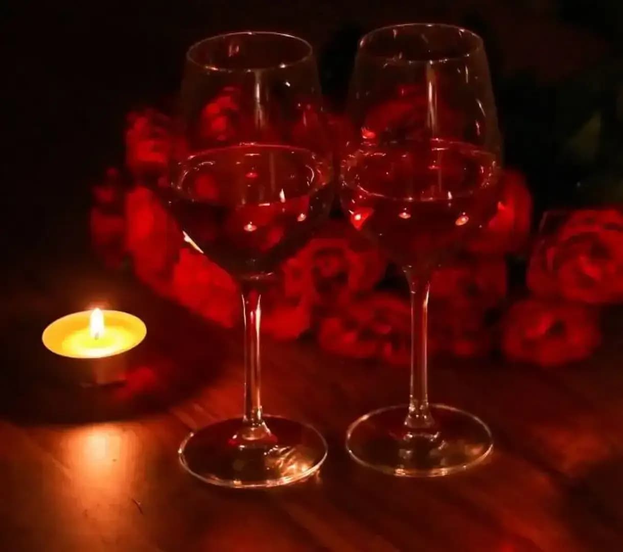 Candlelit wine glasses with a bouquet of roses